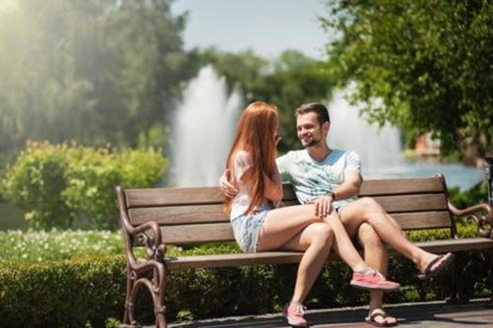人の多い公園のベンチでイチャイチャするカップル
