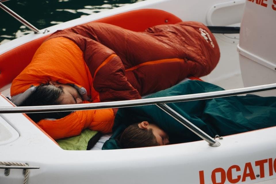 船の上で寝袋を敷いて寝ている親子