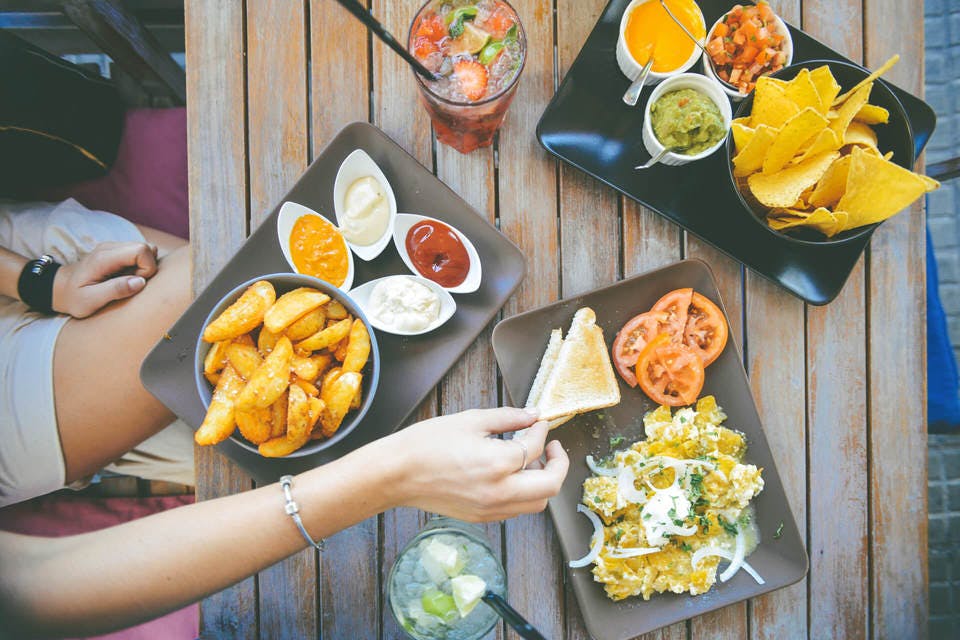 Large womans hand taking food from cafe table with dips and drinks