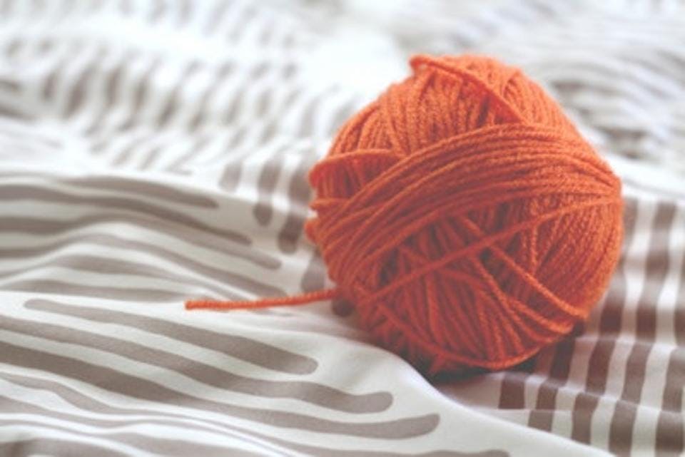 布の上に置かれたダイソーのオレンジ色の毛糸