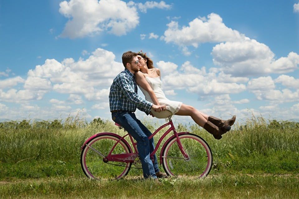 手を繋ぐカップルが自転車に乗る
