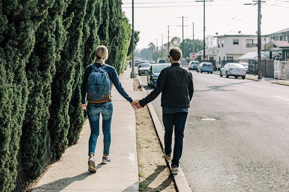 手を繋いで歩道を歩くカップル