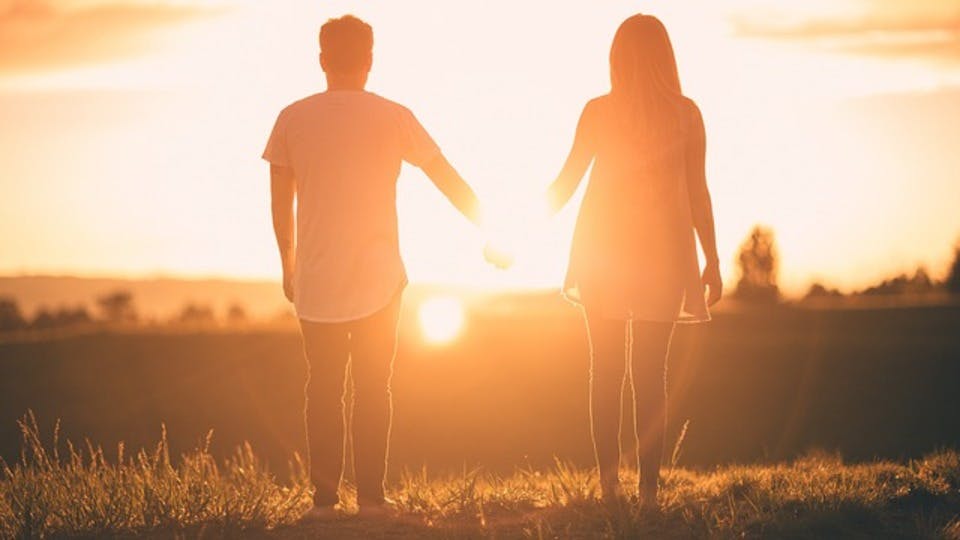 手を繋いで太陽を見るカップル