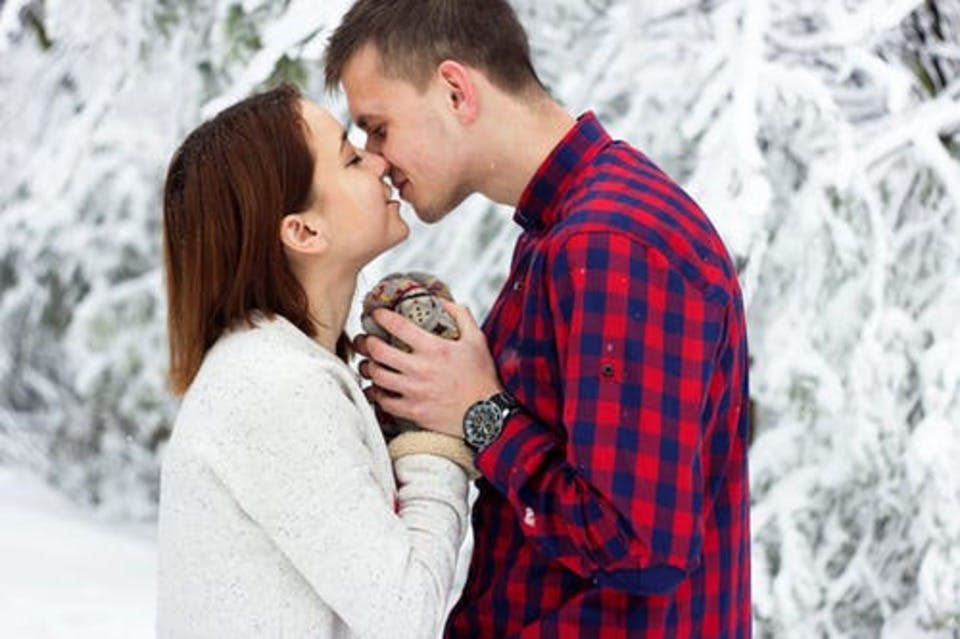 雪の中初めてのキスをする男女