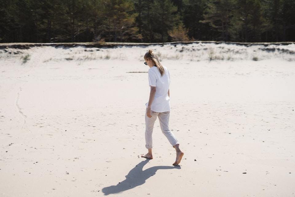 白スキニーで海辺を歩く女性