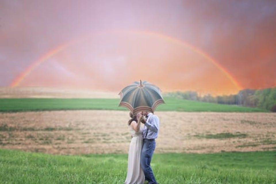 虹の下で激しいキスをする男女