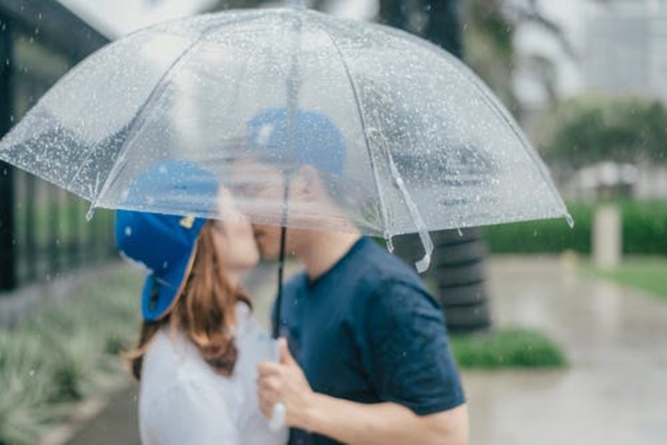 傘の下で激しいキスをする男女