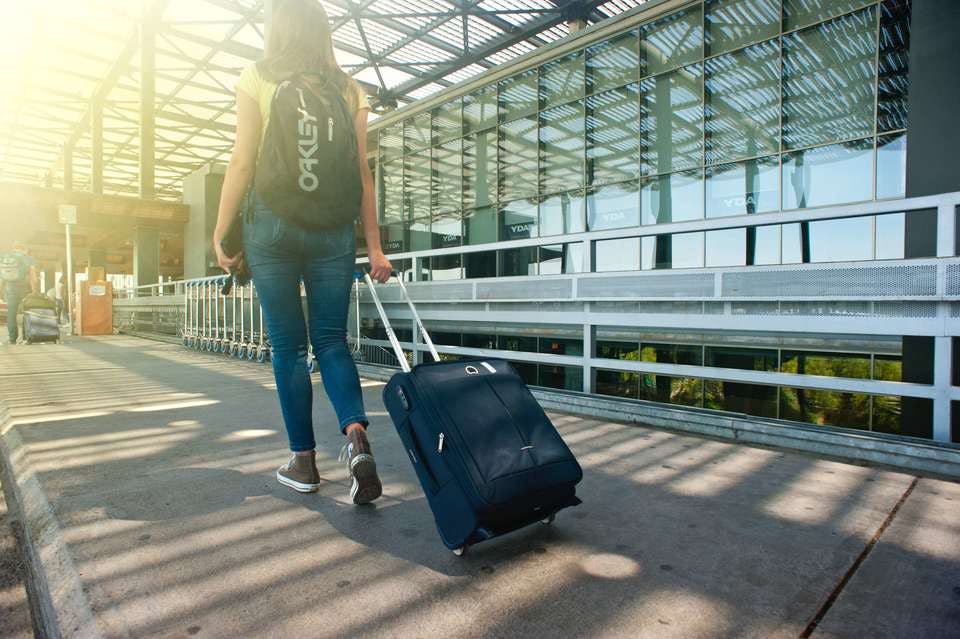 空港でスーツケースを引いて歩く女性