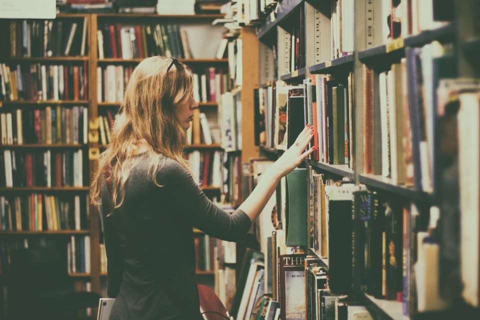 図書館でプラス思考の本を探す女性