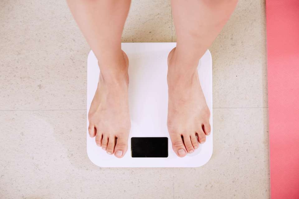 カロリーを気にしてかつやを食べた後体重計に乗る女性