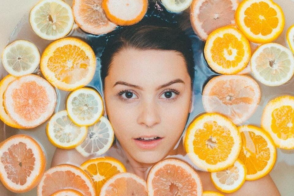柑橘類に囲まれている黒髪の似合う女性
