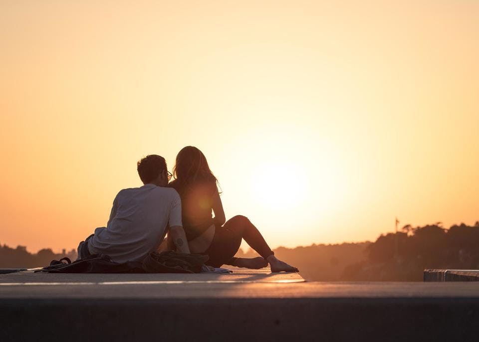 遠距離の彼氏と夕日を眺めるカップル