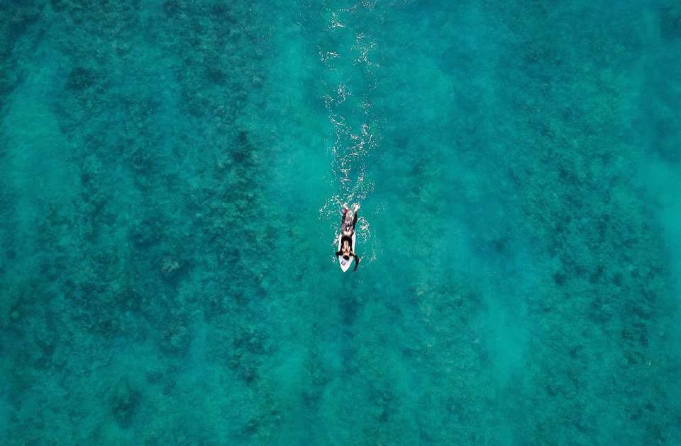 グアムの海でパドリングするサーファー