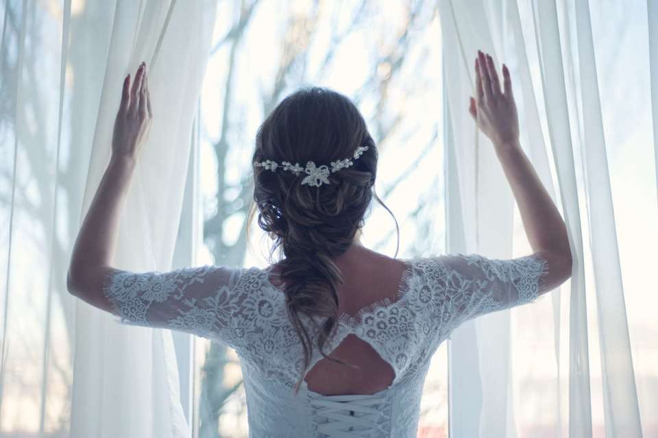 幸せな結婚をした女性がカーテンを開ける