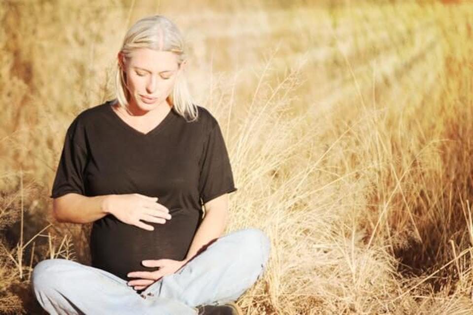 草原に座る妊婦
