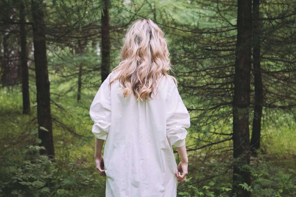 白シャツワンピコーデで森を歩く女性
