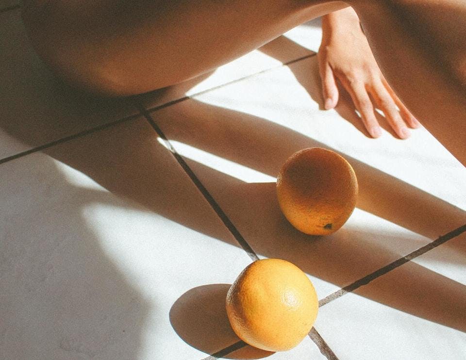 お風呂場にいる女性と2つのオレンジ