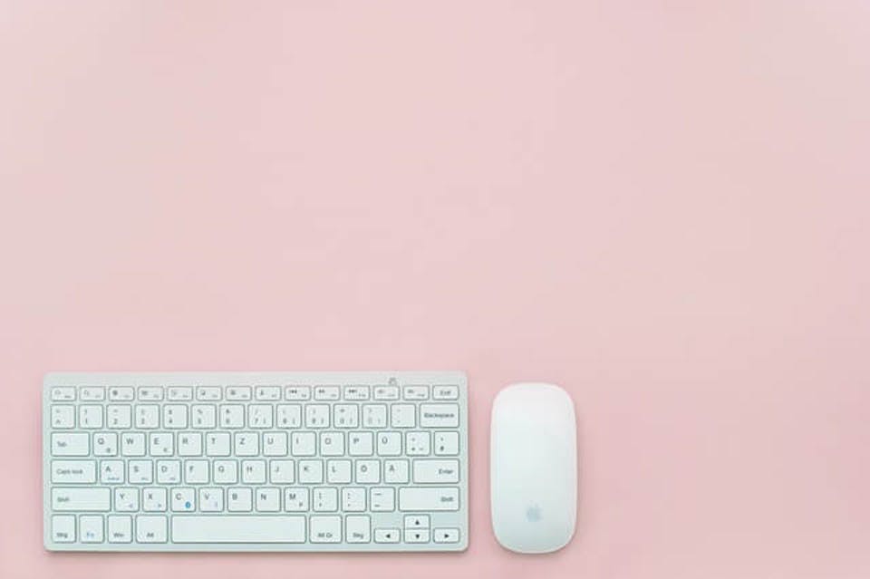 ピンクを背景にしたキーボードとマウス