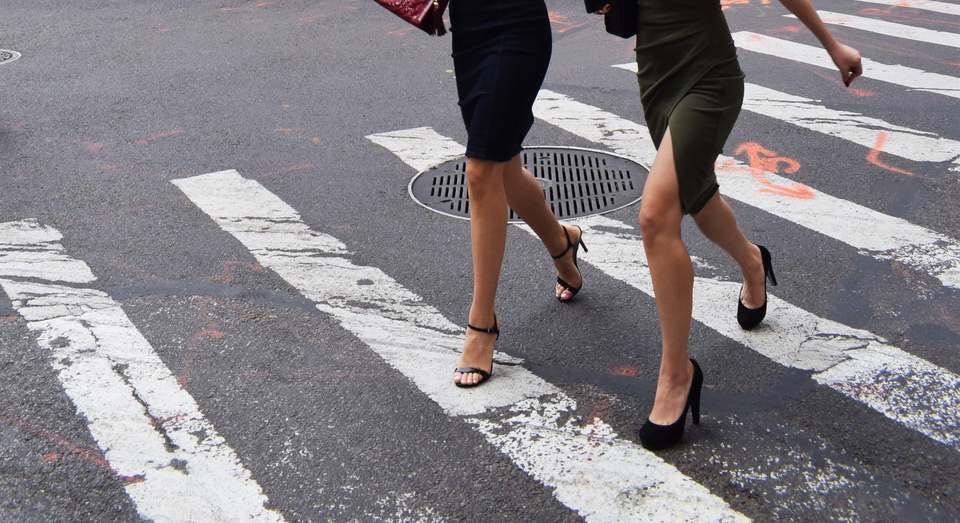 毅然とした女性が二人で横断報道を歩く