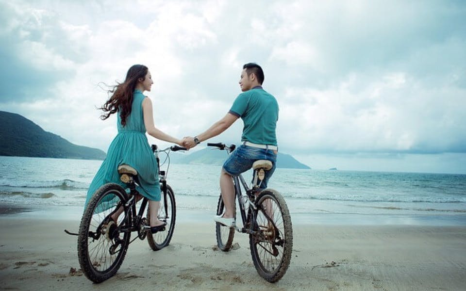 砂浜で自転車に乗るカップル