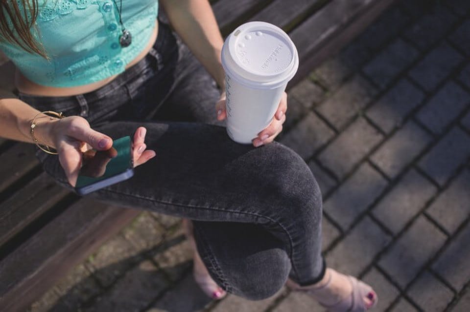 カフェナンバーの人気タピオカメニューを公園で飲んでいる女性