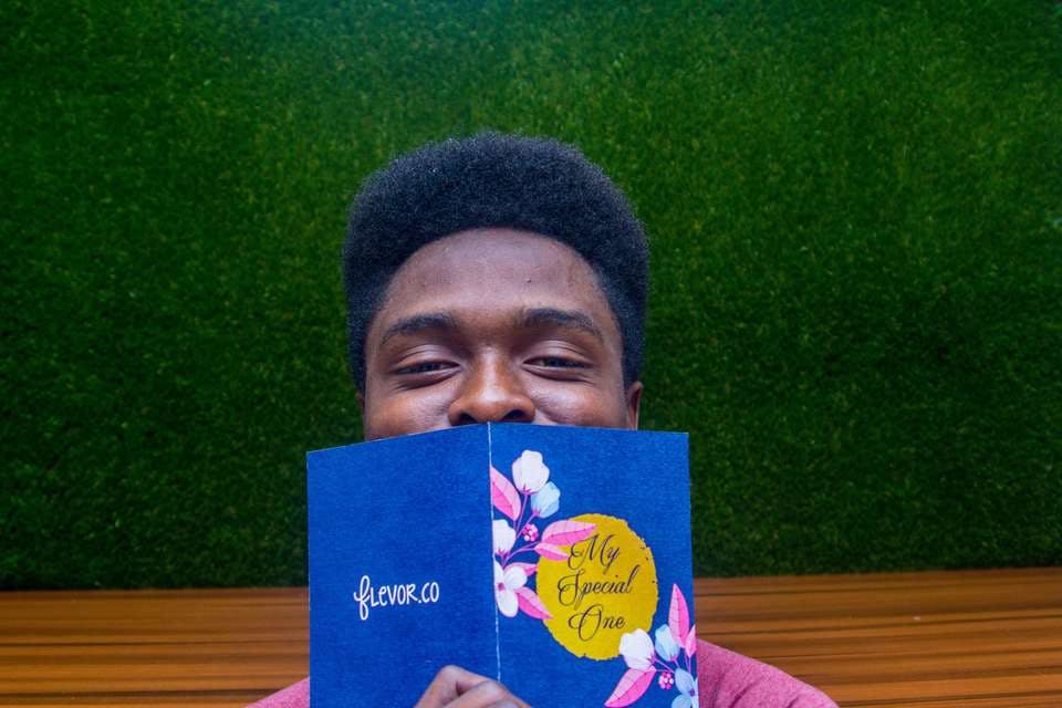 本で口を隠す笑顔のナイジェリア人