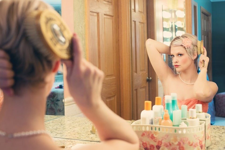 鏡の前で前髪アップスタイルを作る女性