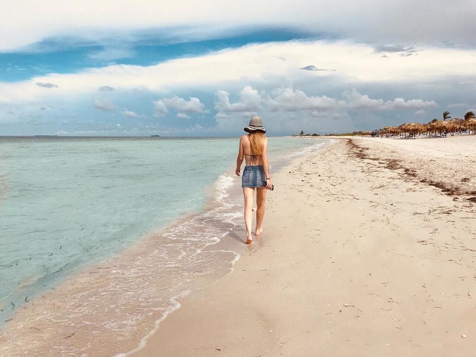 デニムタイトスカートを履いたビーチを歩く女性
