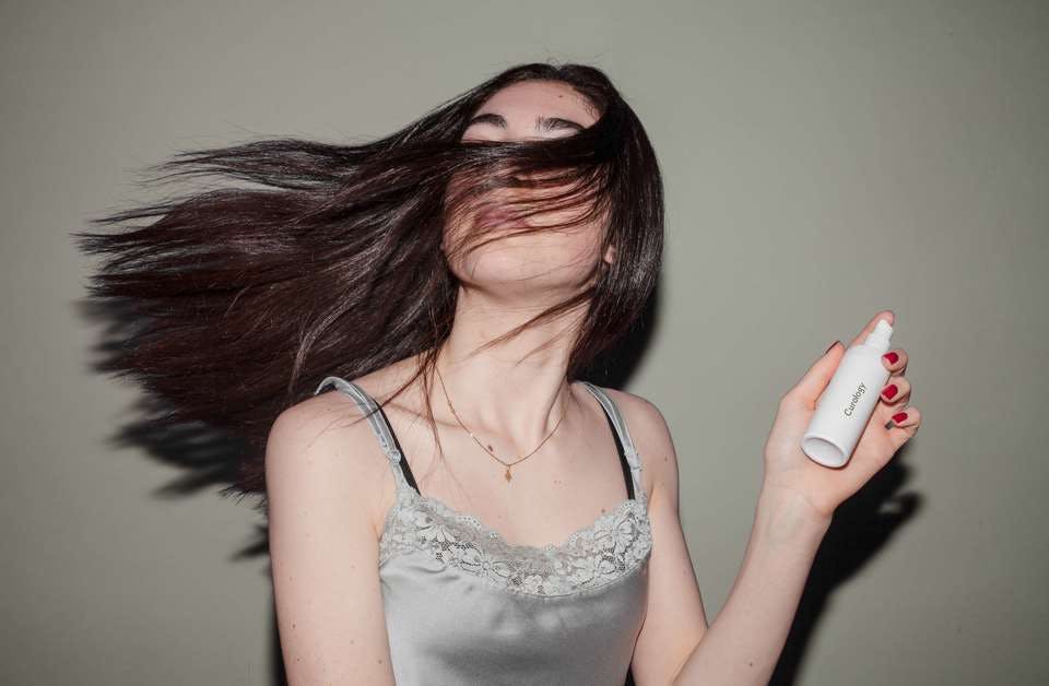うねる髪の毛に役立つアイテムを持つ女性