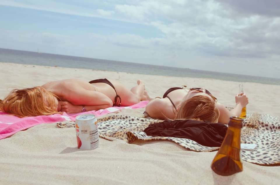 日焼け止めを浜辺で塗り直しする女性