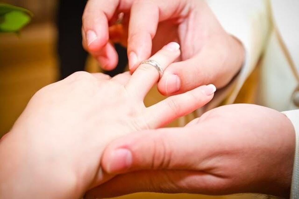 プロポーズの言葉と一緒に女性の指に婚約指輪をはめる男性の手