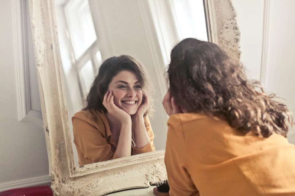 話しかけやすい女性が鏡を見て笑顔を練習する